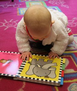 Enfant à la crèche regardant un livre en anglais