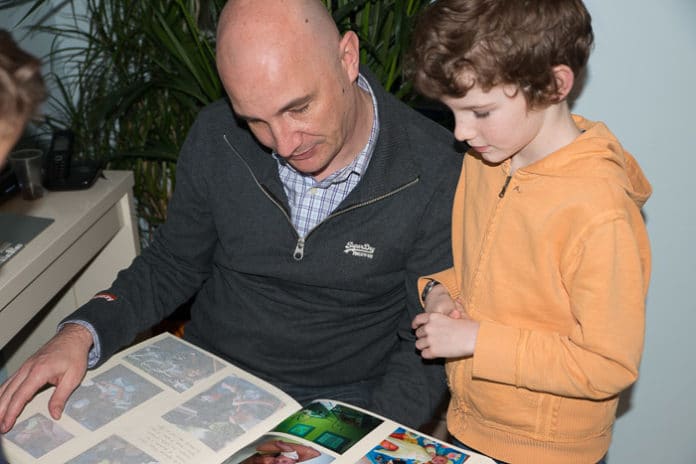 transmettre-langue-maternelle Un papa regarde un album photo avec son fils