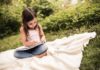Une petite fille révise ses devoirs de vacances en français dans un jardin