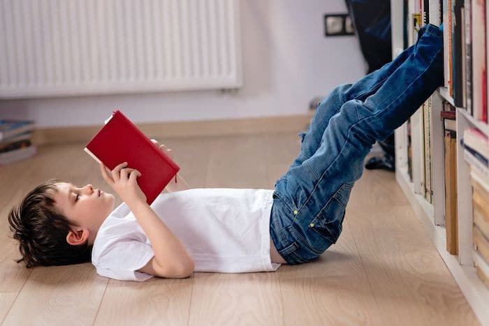 Un enfant prend plaisir à lire un livre allongé par terre