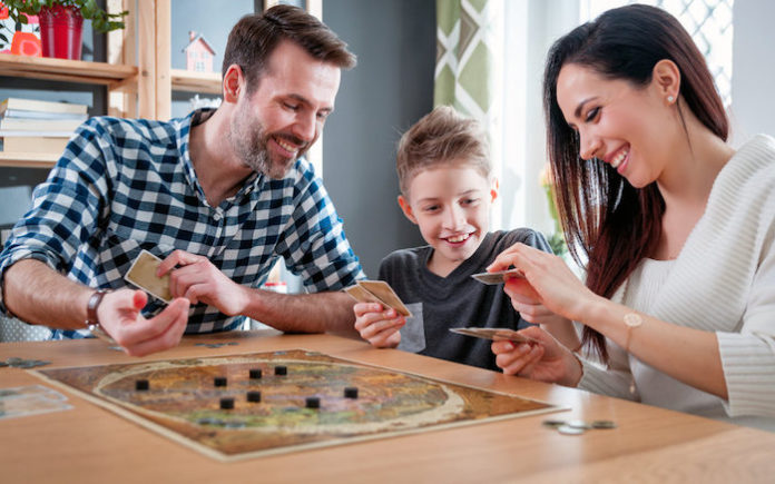 Jeux en anglais pour enfants et adultes Un enfant joue avec sa famille à un jeu de société pour apprendre l'anglais
