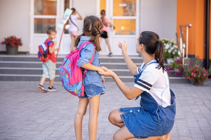 Préparer ses enfants au retour à l'école française Une maman et sa fille devant une école française