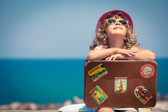 Enfant rêveur avec sa valise lors d'un voyage à l'étranger