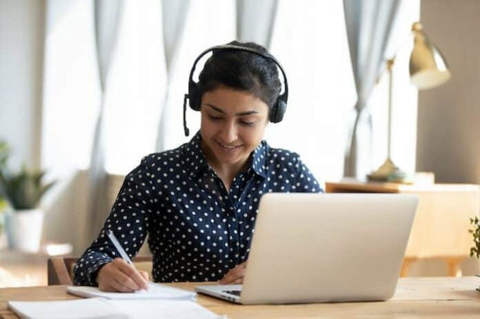 Cours en ligne avec un prof de langue Une jeune femme avec un casque prend un cours en ligne avec son prof de langue à distance