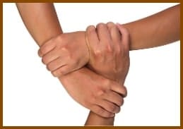 3 mains se tiennent les unes aux autres, illustrant la relation entre l'élève, le professeur et le parent expatrié