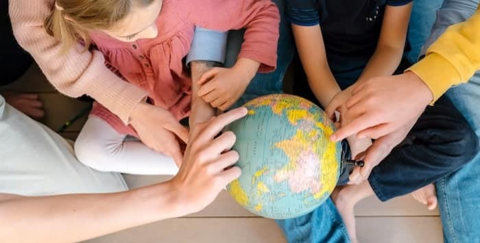Une famille expatriée regarde un globe et s'interroge sur la scolarité à l'étranger