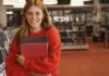 Une adolescente tient ses livres d'école dans la bibliothèque d'un internat anglais